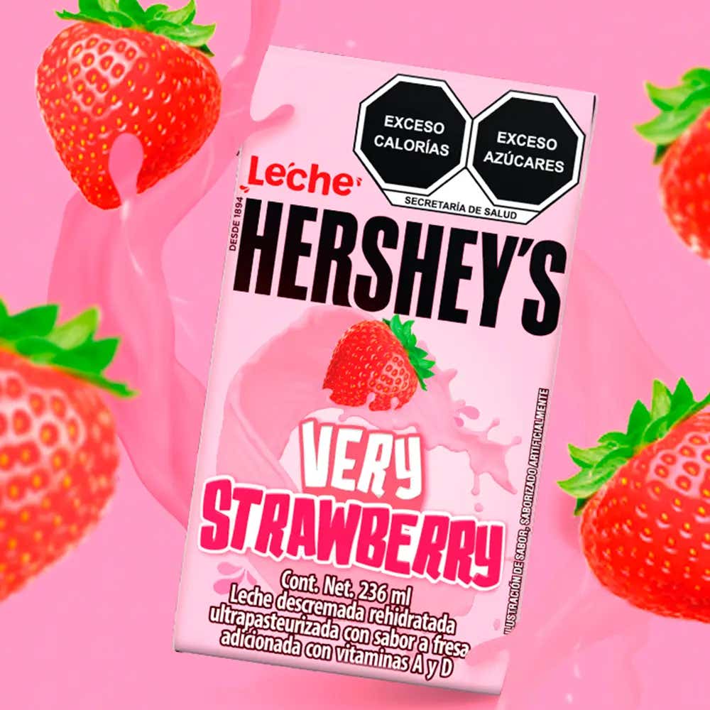 Leche HERSHEY'S sabor Fresa flotando sobre fondo rosa con un splash de fondo y fresas