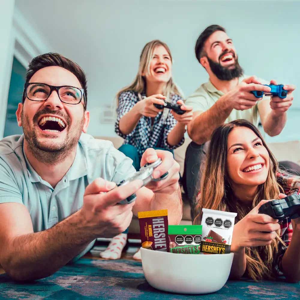Grupo de amigos sonriendo jugando videojuegos en la sala de estar.