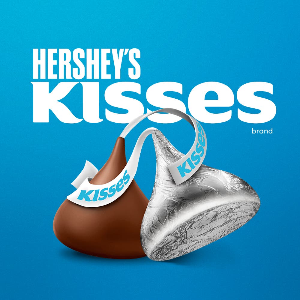 Se muestra la marca HERSHEY'S KISSES, con 2 KISSES Milk al frente, uno sin envoltura y otro al frente con su envoltura de aluminio tradicional.