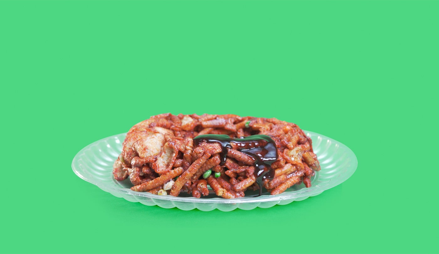 Rosca enchilada hecha a base de PELON PELO RICO, papas fritas, churritos, cacahuates, piñitas enchiladas y PELONETES sobre una charola plástica.