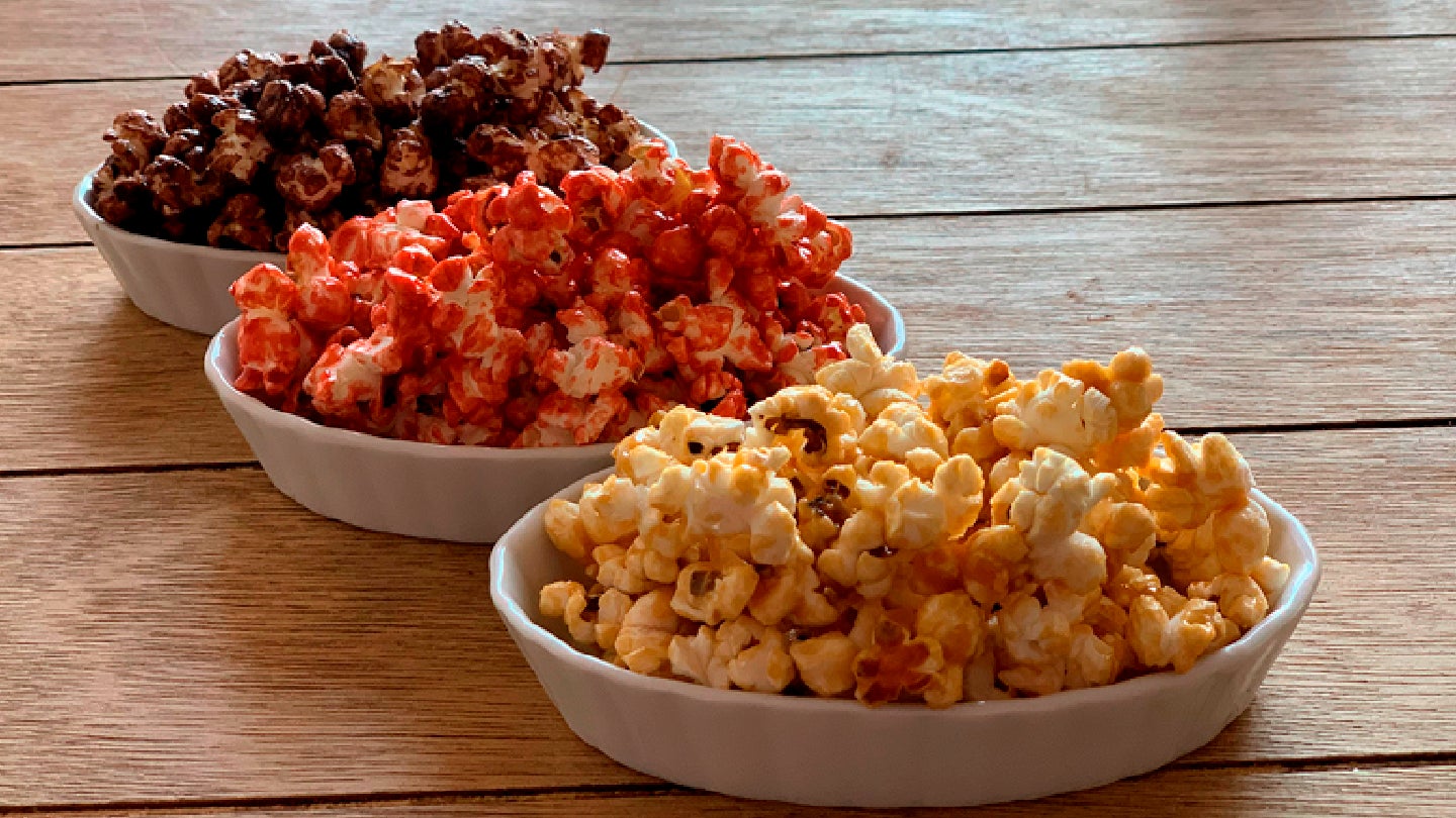 Platos blancos con 3 sabores diferentes de palomitas sobre una mesa de madera.