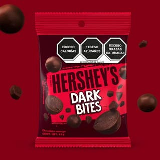HERSHEY'S Bites Dark 43 g sobre un fondo color rojo. Sobre el fondo se observan trozos de chocolate y HERSHEY'S Bites Dark. 