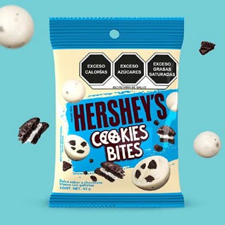 HERSHEY'S Bites Cookies n' Creme 43 g sobre un fondo color azul. Sobre el fondo se observan trozos de galletas y HERSHEY'S Bites Cookies n' Creme. 