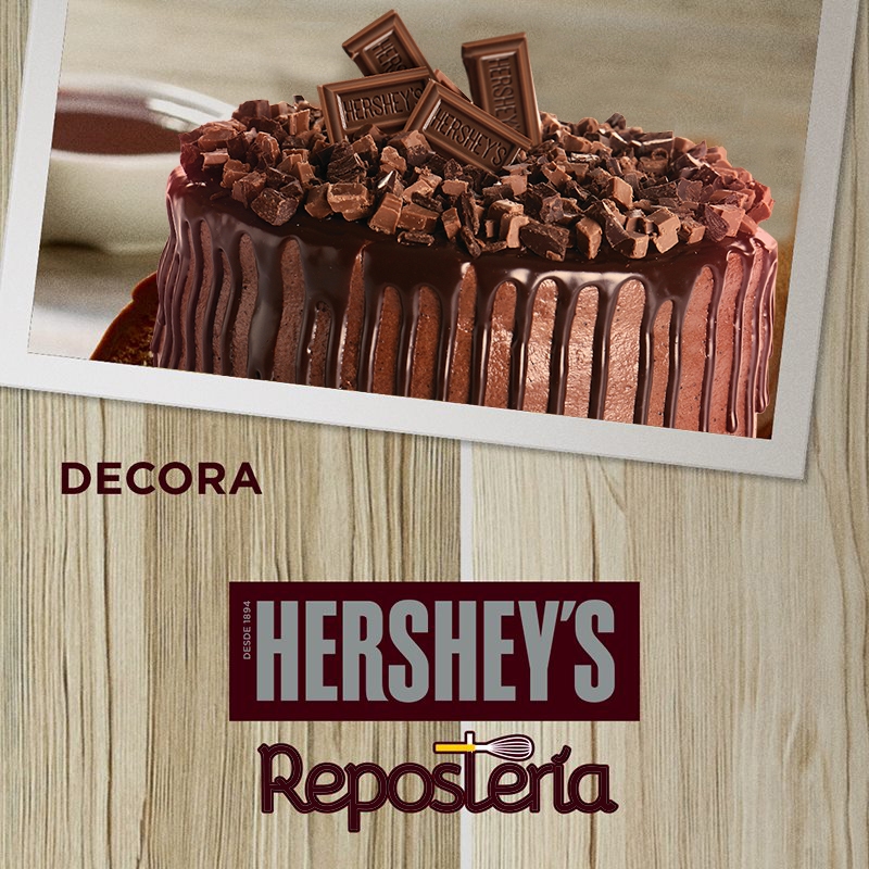 Decora.  Sobre un fondo con textura de madera se ve una fotografía de un postre de Chocolate decorado con frutos rojos, una rosa y chocolate.