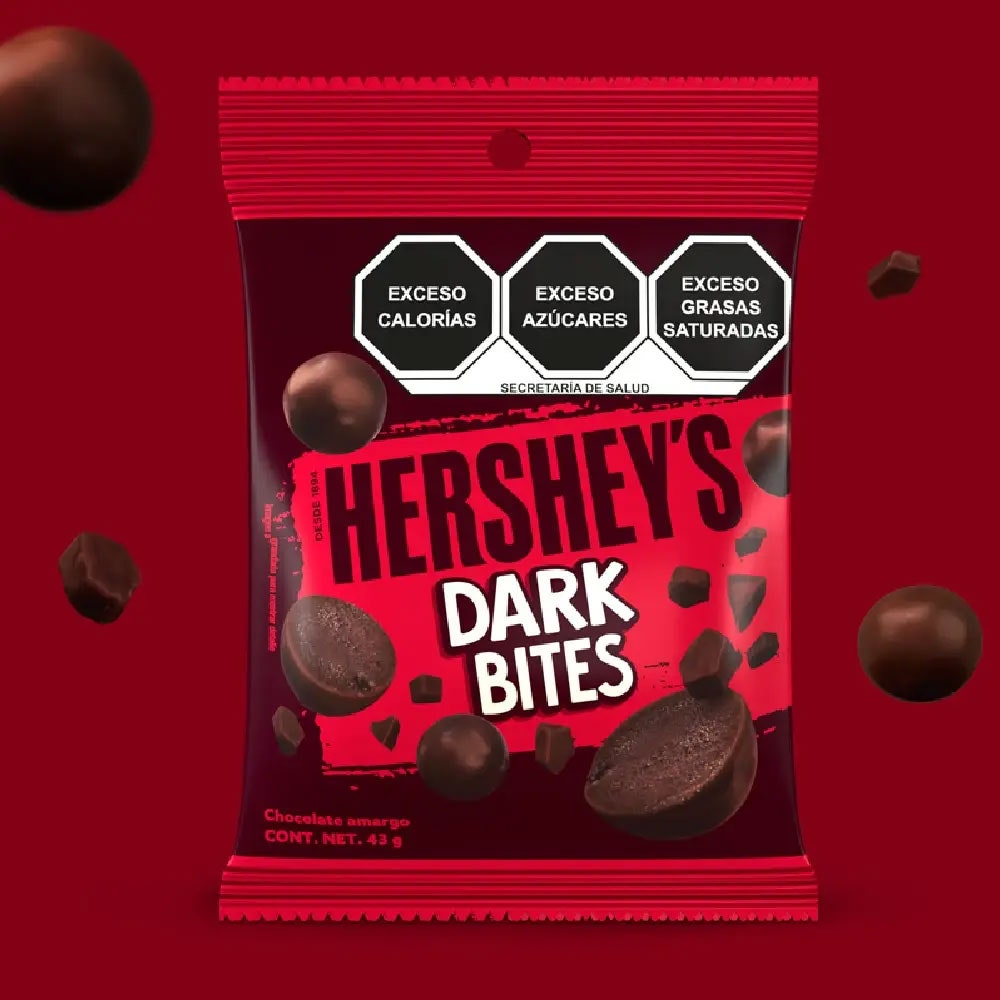 HERSHEY'S Bites Dark 43 g sobre un fondo color rojo. Sobre el fondo se observan trozos de chocolate y HERSHEY'S Bites Dark. 