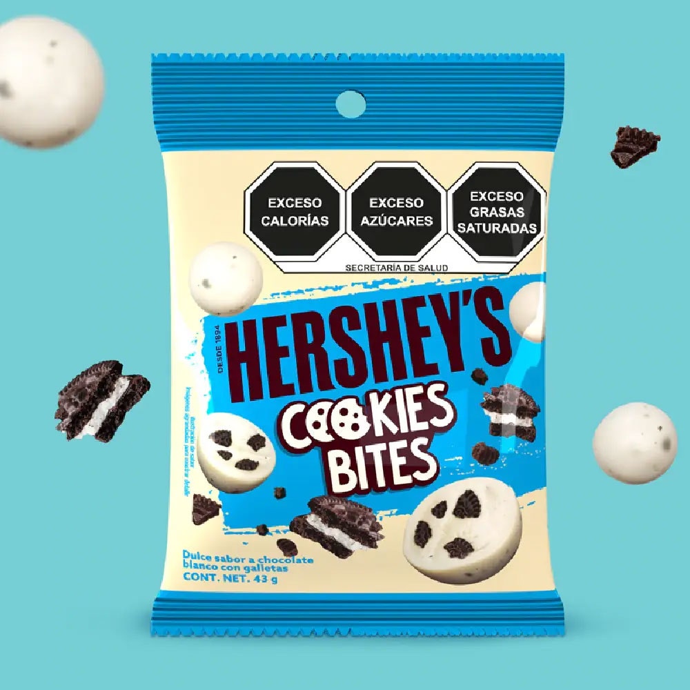 HERSHEY'S Bites Cookies n' Creme 43 g sobre un fondo color azul. Sobre el fondo se observan trozos de galletas y HERSHEY'S Bites Cookies n' Creme. 