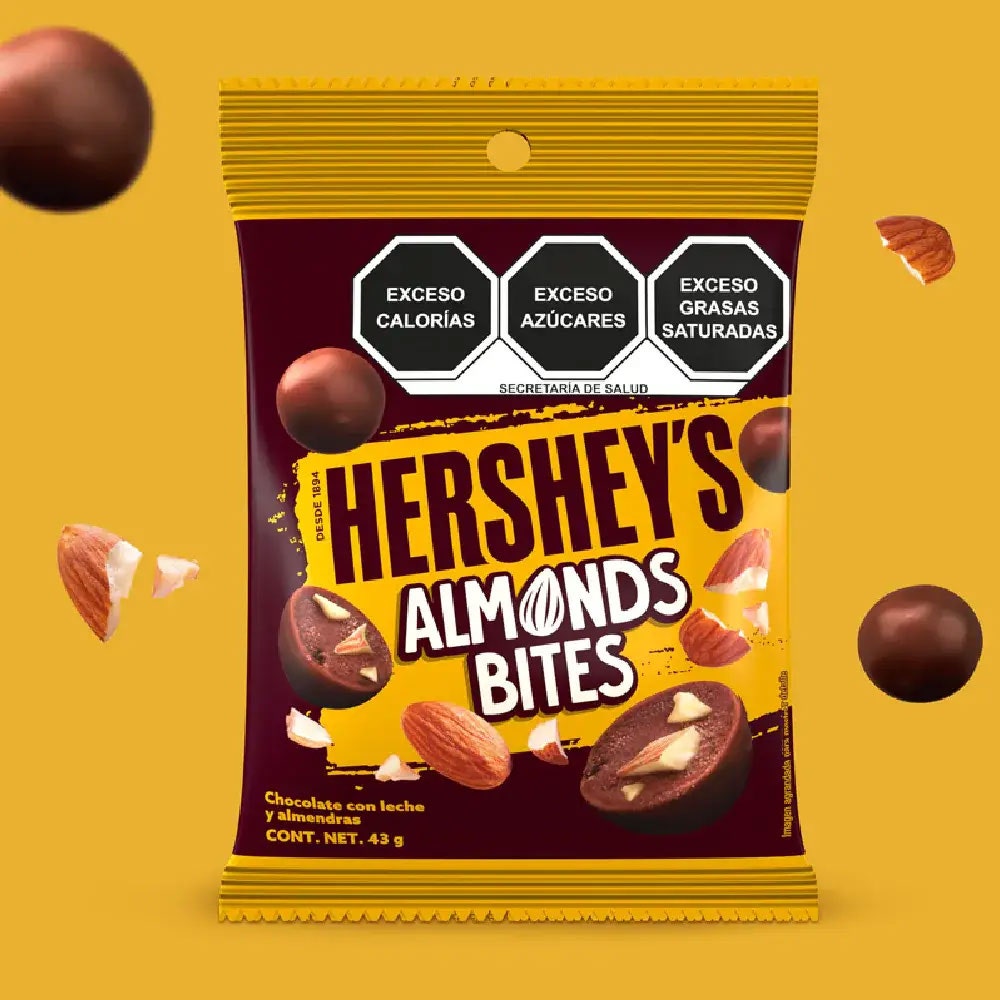 HERSHEY'S Bites Almendra 43 g sobre un fondo color mostaza. Sobre el fondo se observan trozos de almendra y HERSHEY'S Bites Almendra. 